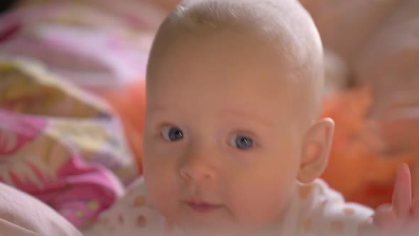 A Closeup of a Cute Baby Girl on Colorful Bed Linen