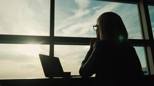 A Woman in a Business Suit Looks Out the Window of Her Office. Concept - Look Ahead in Business