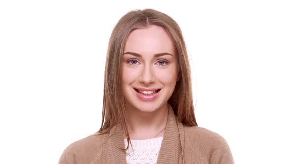 Attractive Young Caucasian Female with Light Brown Hair Looking at Camera Laughing Standing on White