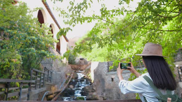 Woman Photographing Flowing Stream