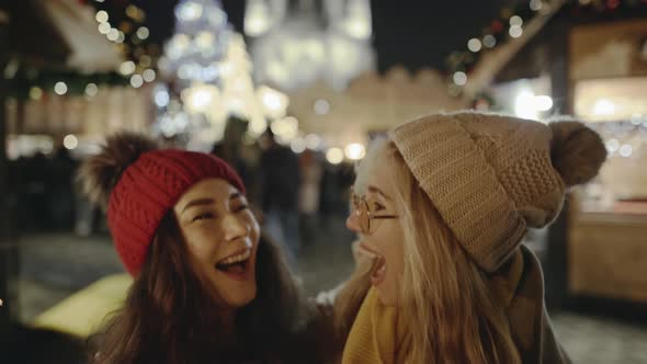 Charming Girls Lesbians Couple Meeiting and Hugging at Festive Street Fair on New Year's Eve