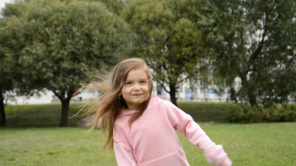 Happy Little Girl Jumping and Rejoicing in the Park