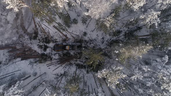 Top down Aerial view of harvester logging a trees in the winter forest 13