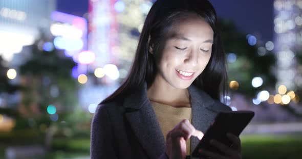 Asian Woman use of cellphone in city at night