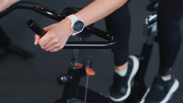 Closeup Athletic Woman Spinning Exercising Workout on Stationary Cycling Machine Bike Indoors