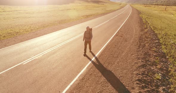 Flight Over Hitchhiker Tourist Walking on Asphalt Road