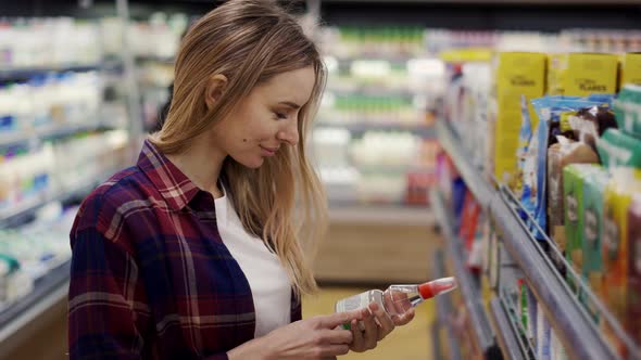 Woman Walks in the Store and Examines the Goods on the Shelves