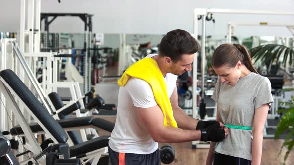 Fitness Trainer Measuring Waist of Female Client.