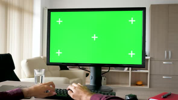 First Person View - Man Hands Typing on Computer Keyboard with Big Green Screen Chroma Mock-up