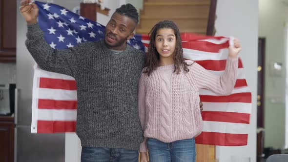 Happy African American Adult Man and Teen Girl Posing with USA Flag Smiling and Hugging