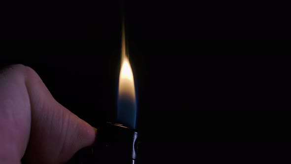 Man Hand with a Lighter Closeup. The Moment of Ignition. Macro Shot of Sparks and Flame on a Dark