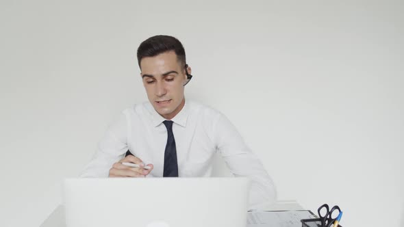 Happy Office Manager with a Earset Provides Online Advice on a Laptop in Office