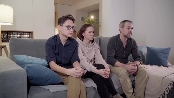 A Family of Three  Father Mother Son and Daughter Watch TV in the Evening