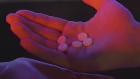 Close-up of Male Hand Pouring Pills in Female Palm. Unrecognizable Drug Dealer Trading Narcotics in