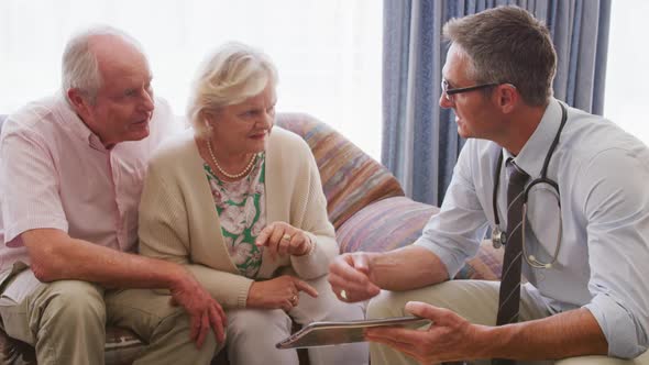 Senior couple talking with a doctor in retirement house