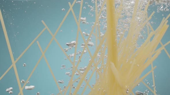 Spaghetti Throwing Into the Water on Blue Background Pasta Falling Into Water