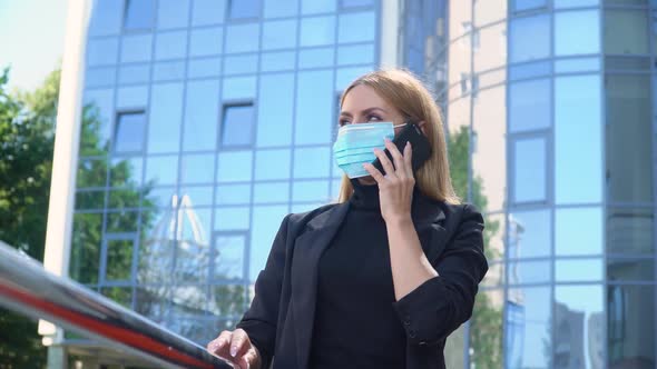 Young Busineswoman in Mask Is Making Call, Standing on City Street, Beautiful Blonde Is Talking 