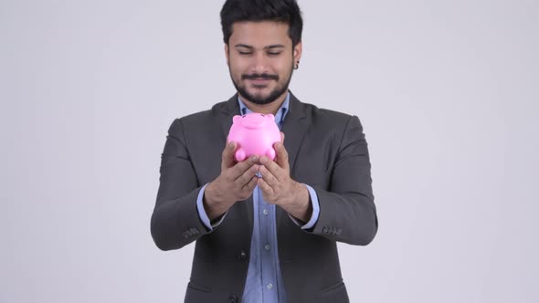 Young Happy Bearded Indian Businessman Giving Piggy Bank