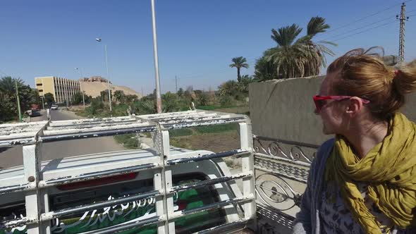 Female tourist and local man riding in the back of pick-up