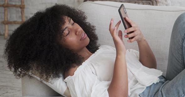 African American Woman Looking at Smartphone Screen Watching Funny Photo Video