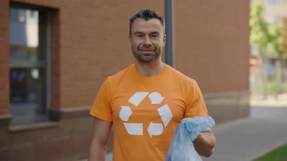 Portrait Male Volunteer Standing and Holding a Garbage Bag with Sorted Garbage Looking at the Camera