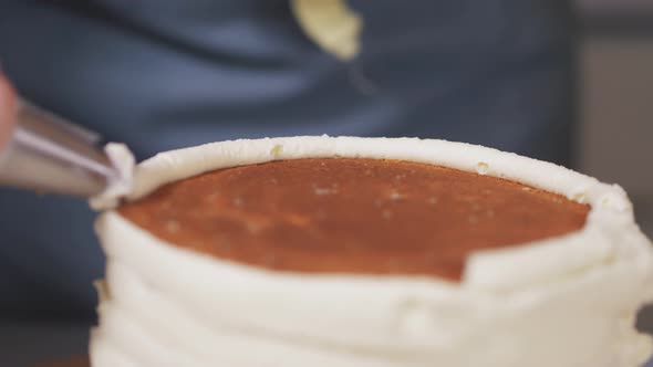 Closeup of the Pastry Chef Applying White Cream on the Side of the Cake