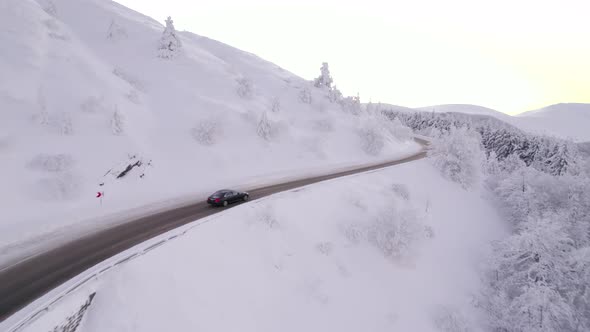 Winter Time Chasing Black Car on Road to Mountain