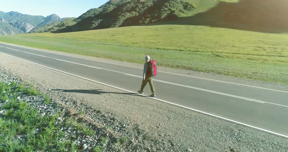 Flight Over Hitchhiker Tourist Walking on Asphalt Road