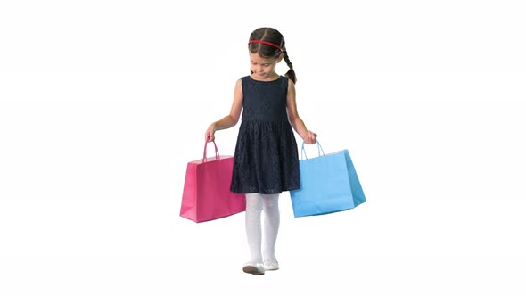Beautiful Little Girl in Black Dress Walking with Shopping Bags on White Background