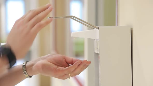 Man at the Entrance To the Clinic Hospital Uses a Sanitizer To Disinfect His Hands