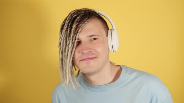 Young Handsome Man in Wireless Headphones Listening to Music Through Mobile Phone