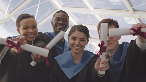 Four Diverse Cheerful Graduates Looking at Camera