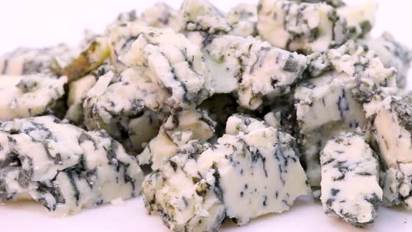 Gorgonzola cheese chopped in small pieces. Rotating close up view in 4k, macro shot.