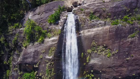 Diyaluma Falls and Bright Rainbow on Steep Cliff in Forest