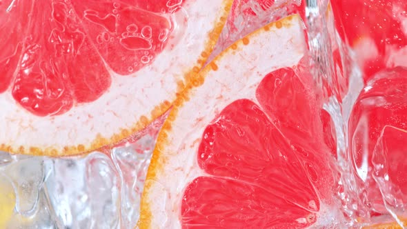 Super Slow Motion Shot of Pouring Water on Grapefruit Slices and Ice Cubes in Glass at 1000 Fps