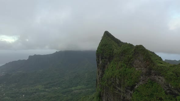 Aerial shot flying alongside a huge cliff in the mountains of Mo'orea island, French Polynesia