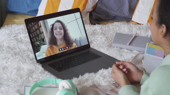 African Teen Girl Talking To Friend in Virtual Video Call Chat on Laptop in Bed