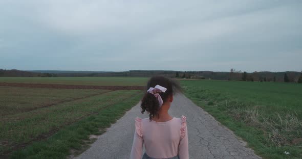 High angle view of little girl walking alone on lost empty field road at sunset in Schonaich Germany