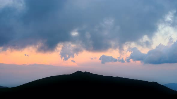 Dark Blue Clouds with Red Sky at The End of The Day. Time Lapse Over the Mountains