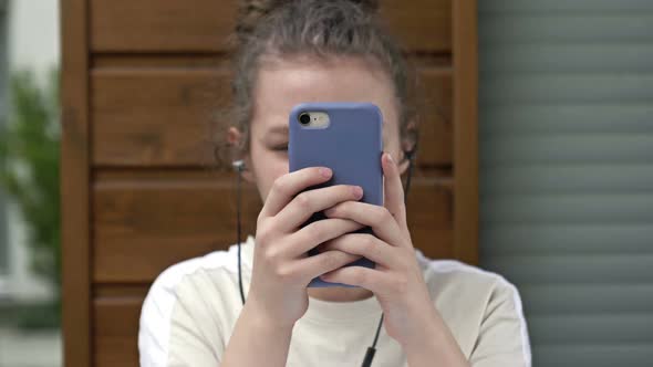 Teen Girl Holding Phone Obsessed with Smartphone Social Media Apps Sitting Alone at Home