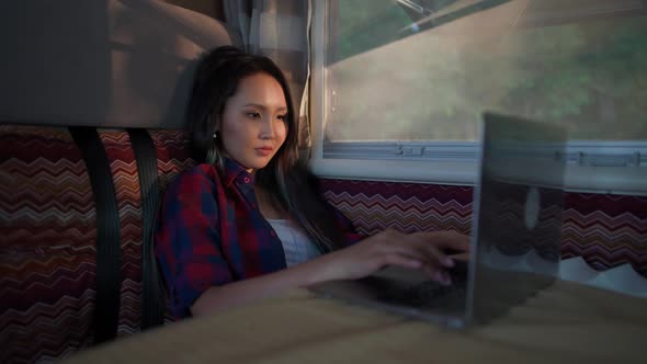 Asian Female Working at a Laptop While Sitting in a Car Typing Text and Remote Work in Nature