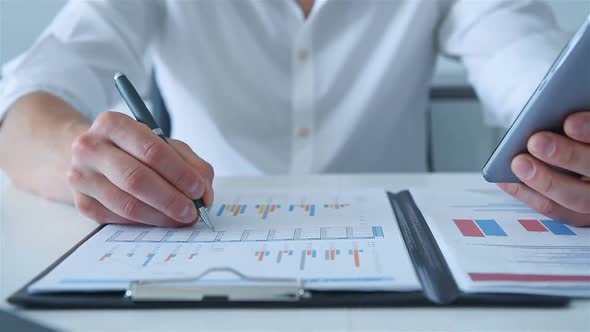 Businessman With Mobile Phone Analyzing Business Plan.