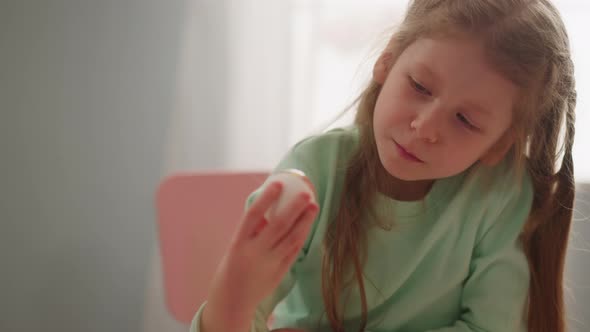 Thoughtful Girl Holds Easter Egg Colored with Marbling