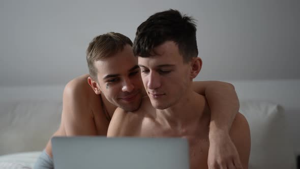 Portrait of Busy Young Gay Man Messaging Online on Laptop As Cheerful Boyfriend Covering Eyes with