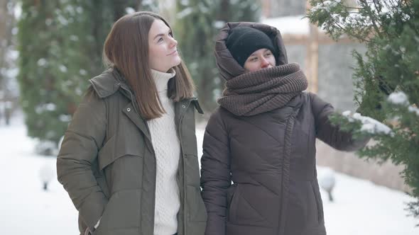 Two Cheerful Young Women Enjoying Winter Weather Outdoors on Snowy Day