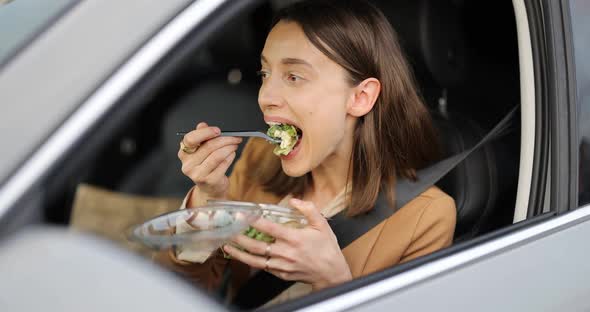 Business Woman Eating a Salad on the Driver's Seat of Her Car