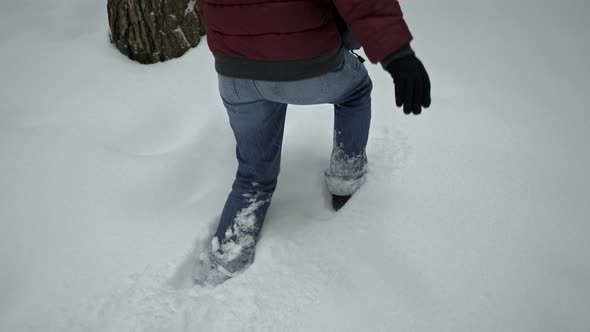 Female's Legs in Blue Jeans Walking through Knee-Deep Snow in the Mountains