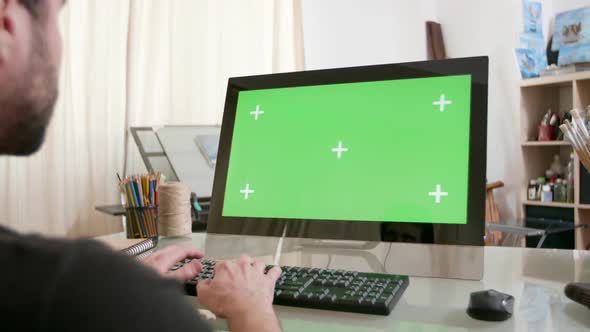 Young Artist Working at His Computer with Green Screen on the Display