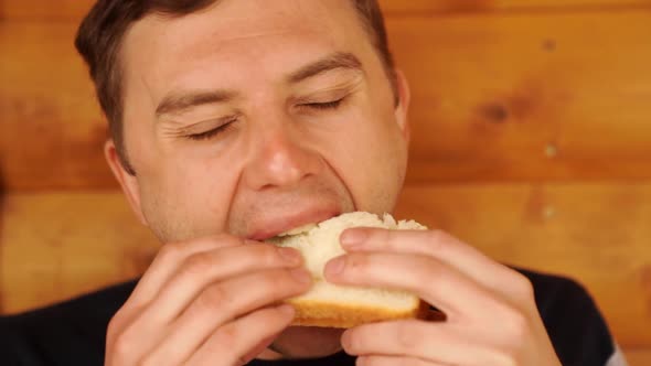 a Man Bites and Eats a Sandwich Made of White Bread