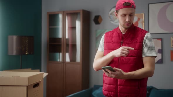 Delivery Man Counting Boxes in New Apartment and Writing Result in Smartphone